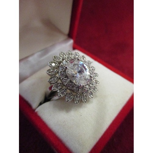 32 - A DRESS RING WITH A LARGE CLEAR CUT STONE SURROUNDED BY PETALS OF SMALLER STONES
