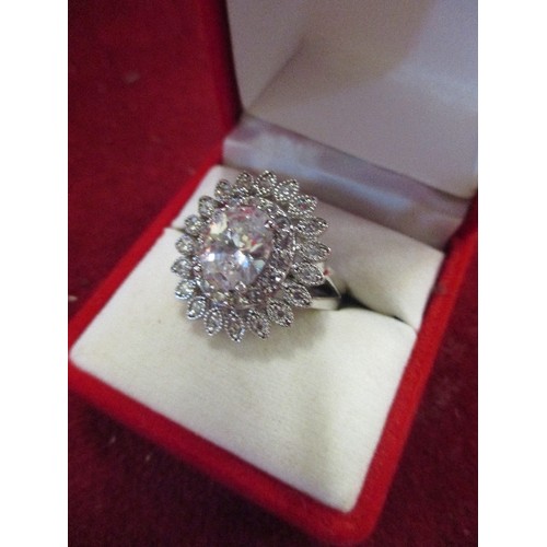 32 - A DRESS RING WITH A LARGE CLEAR CUT STONE SURROUNDED BY PETALS OF SMALLER STONES