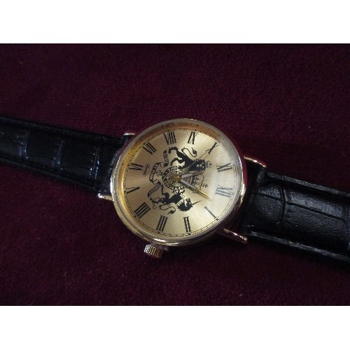 25 - EIGER WRIST WATCH WITH ROYAL CREST ON THE GILT FACE - BLACK LEATHER EFFECT STRAP