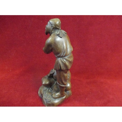 184A - 20TH CENTURY ORIENTAL CARVED WOOD FIGURE OF A MAN ON ROCKS WITH TRAILING LEAVES - 21CM