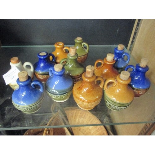 242 - COLLECTION OF MINIATURE GLAZED STONEWARE DECANTERS WITH CORK STOPPERS. EACH HAS A DIFFERENT NAME IE ... 