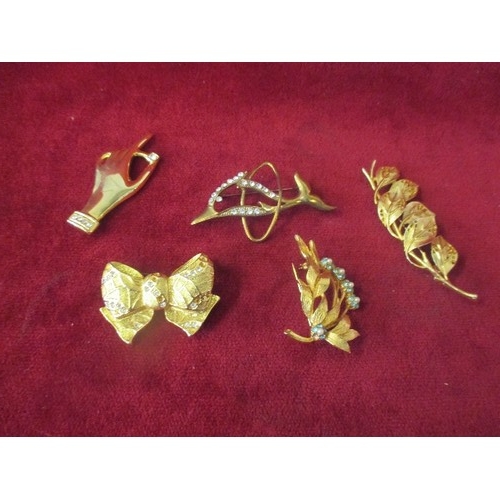 44 - 5 X GILT METAL BROOCHES INCUDING A HAND HOLDING A DIAMANTE, A BOW, A LEAPING DOLPHIN