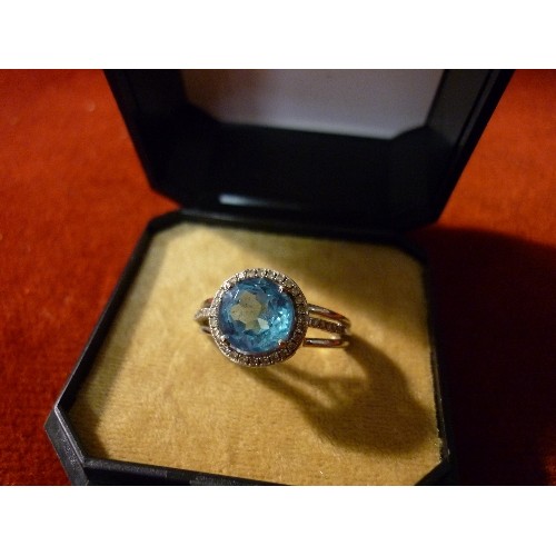 34 - WHITE GOLD BIRMINGHAM HALLMARKED RING SET WITH LARGE PALE BLUE STONE SURROUNDED BY 