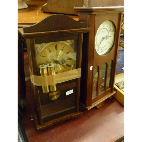 229 - 2 WALL CLOCKS WITH PENDULUMS. IN GLASS/WOOD CASES. ROMAN NUMERALS.