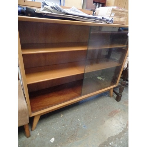 276 - MID CENTURY GLASS FRONTED WALNUT VENEERED BOOKCASE WITH SLIDING GLASS DOORS ON SPLAYED LEGS