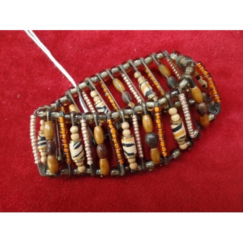 28 - ETHNIC BEADED BRACELET OF GLASS WOOD AND METAL HELD TOGETHER WITH SAFETY PINS AS PART OF THE DESIGN