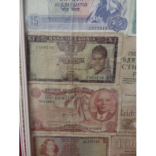 105 - GLAZED FRAME CONTAINING BANKNOTES FROM AROUND THE WORLD. MALAWI, MAURITIUS, REPUBLIC OF BIAFRA, ZAMB... 