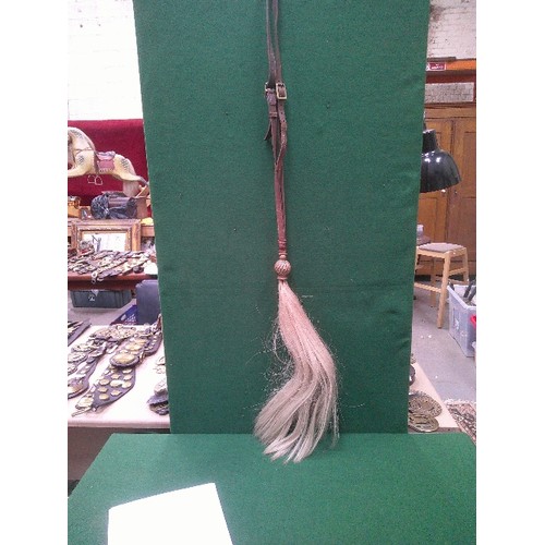 401 - AN ANTIQUE WHITE HORSE HAIR HANGING PLUME WITH BRASS SPIRAL BALL MOUNT AND LONG LEATHER STRAP. LENGT... 