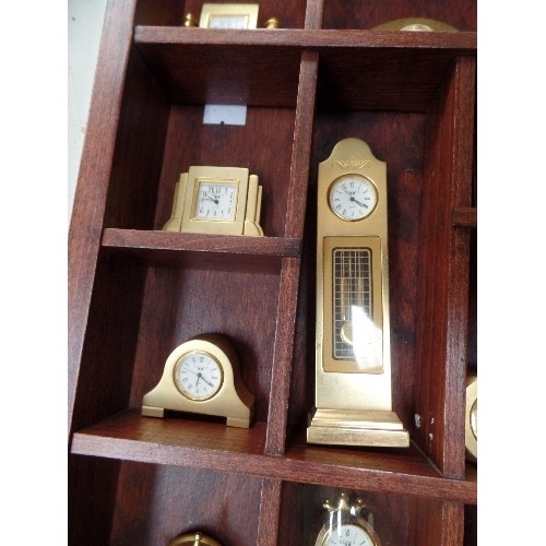 202 - 24 MINIATURE BRASS CLOCKS IN A WOODEN DISPLAY CASE