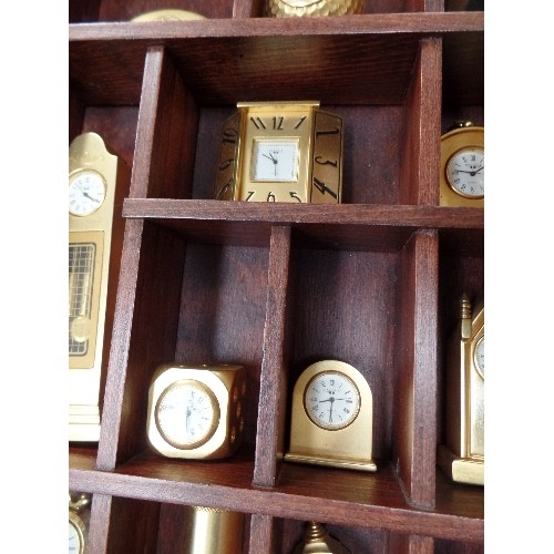 202 - 24 MINIATURE BRASS CLOCKS IN A WOODEN DISPLAY CASE