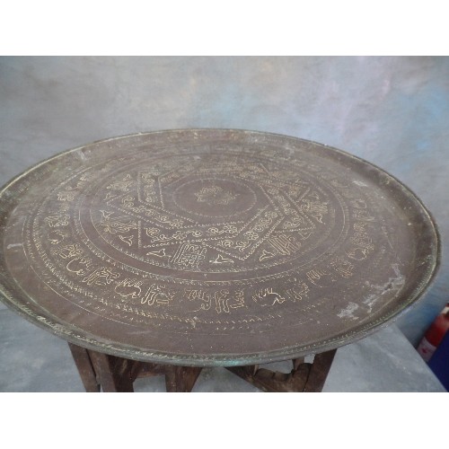 222 - A VINTAGE BENARES TABLE WITH FOLDING BASE AND PERSIAN BRASS TRAY TOP ENGRAVED WITH SCRIPT AND ANIMAL... 