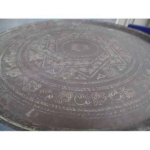 222 - A VINTAGE BENARES TABLE WITH FOLDING BASE AND PERSIAN BRASS TRAY TOP ENGRAVED WITH SCRIPT AND ANIMAL... 