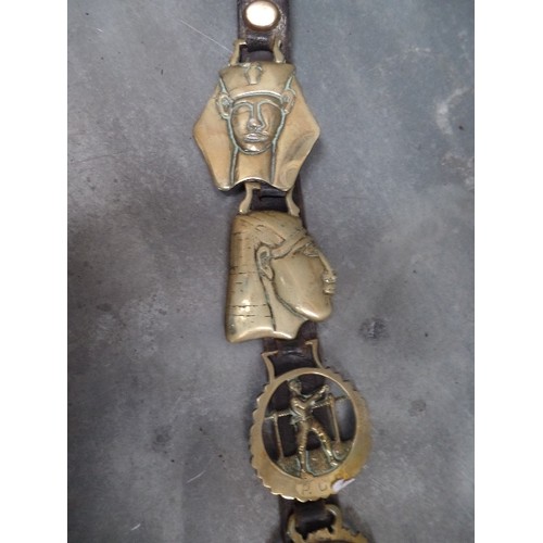 393 - AN ANTIQUE LEATHER STRAP WITH SOME UNUSUAL HORSE BRASSES 19TH & 20TH CENTURIES. INCLUDING WILLIAM GL... 