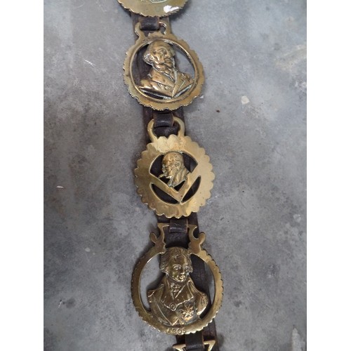 393 - AN ANTIQUE LEATHER STRAP WITH SOME UNUSUAL HORSE BRASSES 19TH & 20TH CENTURIES. INCLUDING WILLIAM GL... 