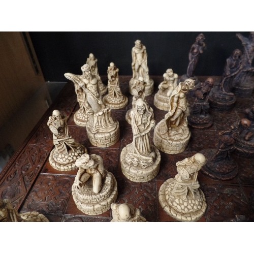 241 - LARGE CHESS SET. CARVED CHESS BOARD. RESIN WARRIOR-SKELETON PIECES.  3 PIECES HAVE BEEN REPAIRED.