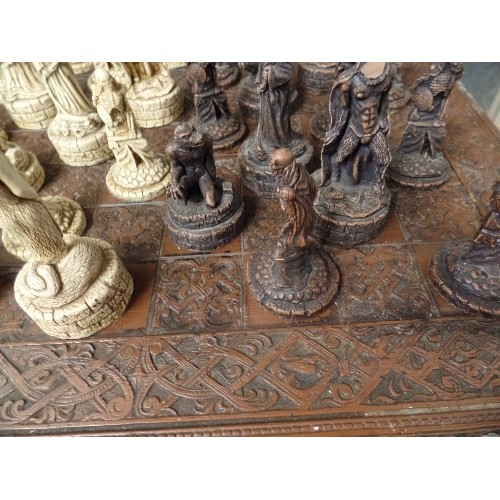 241 - LARGE CHESS SET. CARVED CHESS BOARD. RESIN WARRIOR-SKELETON PIECES.  3 PIECES HAVE BEEN REPAIRED.