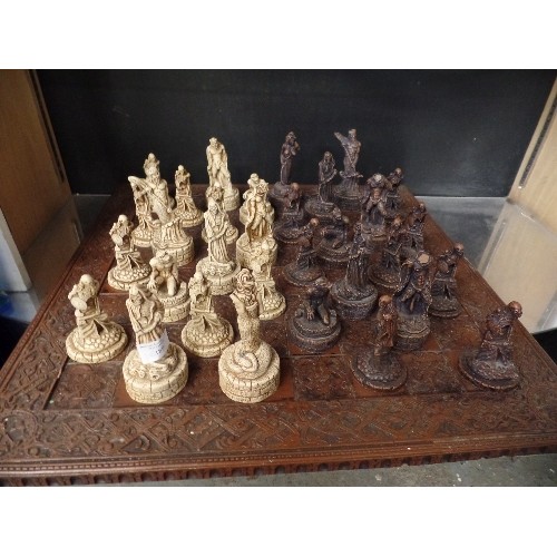 241 - LARGE CHESS SET. CARVED CHESS BOARD. RESIN WARRIOR-SKELETON PIECES.  3 PIECES HAVE BEEN REPAIRED.