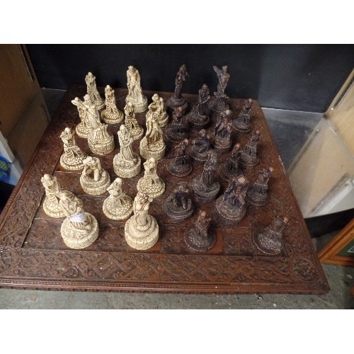 241 - LARGE CHESS SET. CARVED CHESS BOARD. RESIN WARRIOR-SKELETON PIECES.  3 PIECES HAVE BEEN REPAIRED.