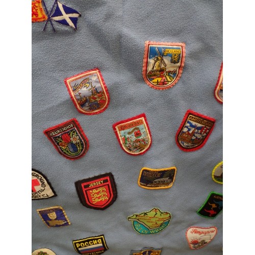 342 - FLEECE DOOR CURTAIN DECORATED WITH LARGE QUANTITY OF SEWN -ON CLOTH SOUVENIR BADGES FROM ALL OVER TH... 