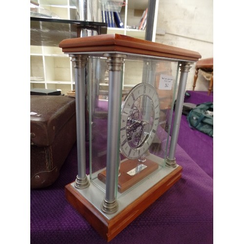 201 - DECORATIVE MANTLE CLOCK. OPEN MECHANISM IS ENCASED IN GLASS.