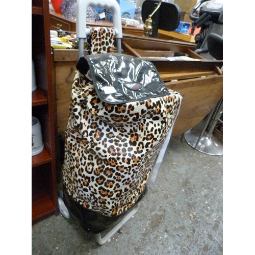 382 - ANIMAL PRINT WHEELED SHOPPING BAG. WATERPROOF FABRIC. FULL OF HOUSEHOLD LINEN, TOWELS ETC.