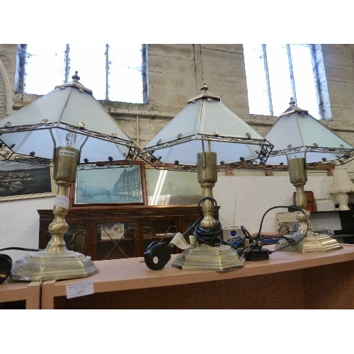 438 - THREE  BRUSHED BRASS TABLE LAMPS. WITH SIMPLE TIFFANY STYLE GLASS SHADES.