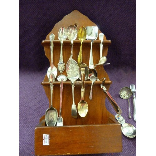 87 - COLLECTABLE VINTAGE SPOONS ON A WOODEN WALL DISPLAY RACK. APPROX 20.