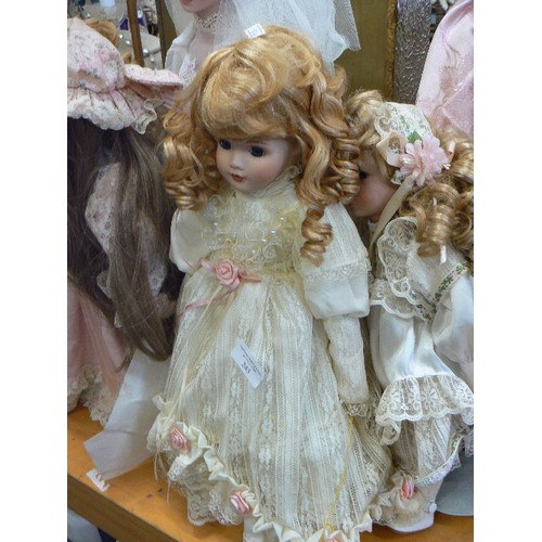 245 - PORCELAIN DOLL COLLECTION. 7 X DOLLS, INC A BRIDE, AND A PIERROT CLOWN ON GOLD CHAIR. .