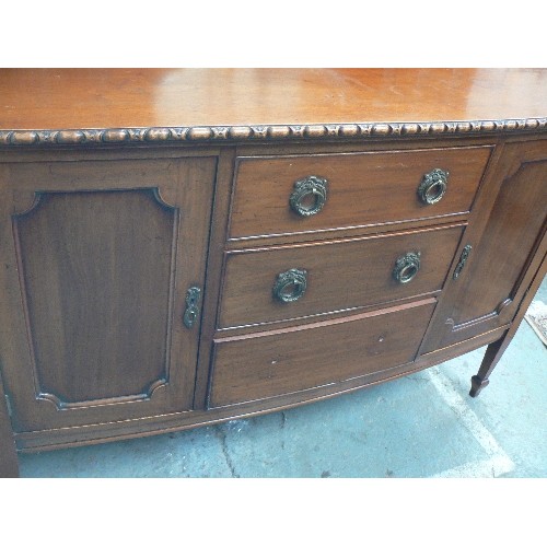 386 - A 1920'S WALNUT BOW FRONTED SIDEBOARD WITH THREE CENTRAL DRAWERS FLANKED BY TWO CUPBOARDS. THE UPSTA... 