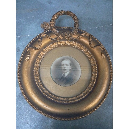 134 - A VICTORIAN CIRCULAR PHOTOGRAPH FRAME IN GILT FINISH WITH A LAUREL WREATH DECORATION - 23CM DIA