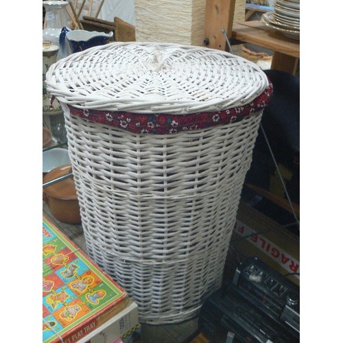 347 - WHITE WICKER LAUNDRY BASKET. BARREL SHAPED, WITH RED FABRIC LINING. CONTAINS 2 TOWELS.