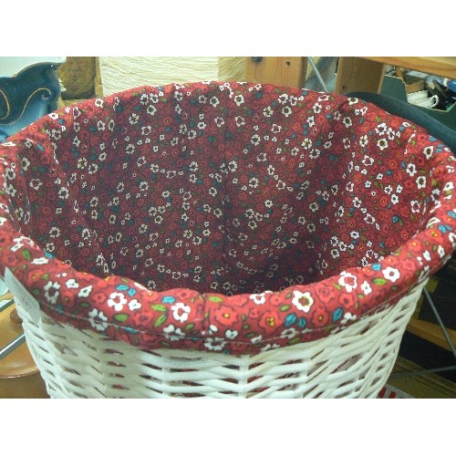 347 - WHITE WICKER LAUNDRY BASKET. BARREL SHAPED, WITH RED FABRIC LINING. CONTAINS 2 TOWELS.