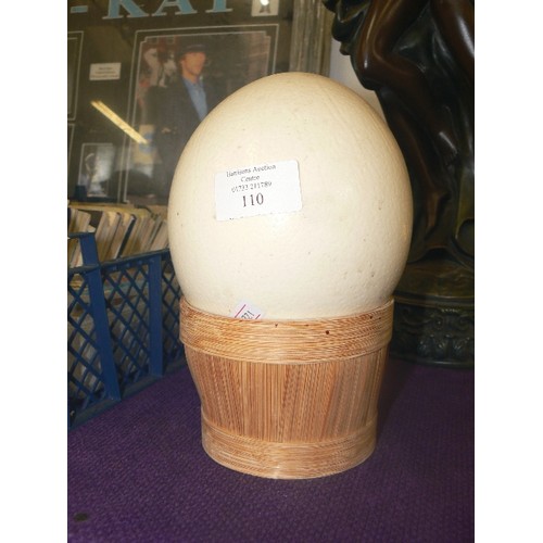 110 - VINTAGE OSTRICH EGG. SITTING IN A BAMBOO BASKET.