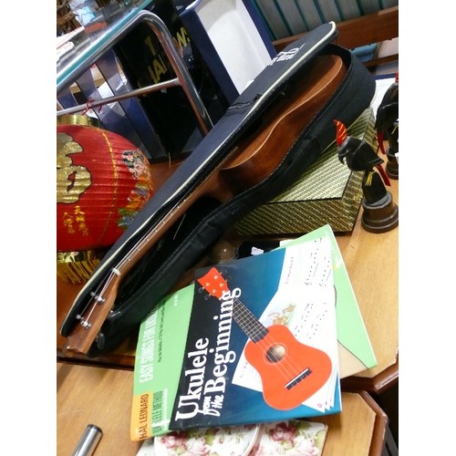 279 - UKULELE BY 'STRONG WIND' IN CASE WITH STRAP AND TWO TUTORIAL BOOKS.