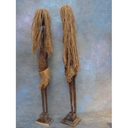 124A - A good pair of tall African tribal female figures in carved wood with jute hair and skirts - the tal... 