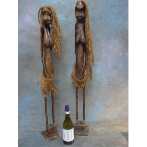 124A - A good pair of tall African tribal female figures in carved wood with jute hair and skirts - the tal... 