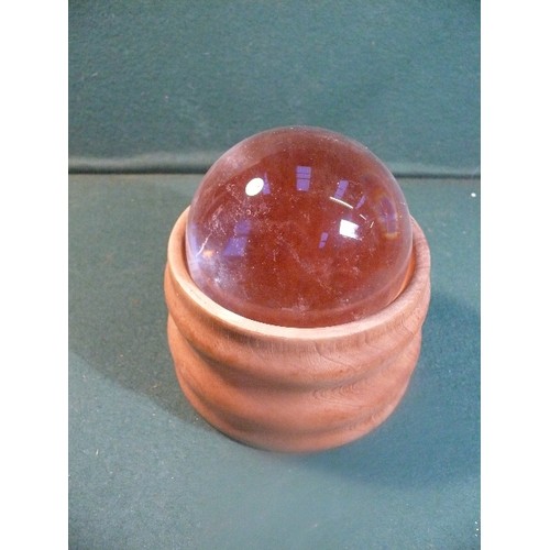 118 - A heavy crystal ball in a turned wood stand. 10.5 cm dia