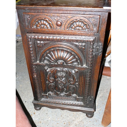 433 - Early to mid 20th Century oak cupboard with drawer, the door deeply carved with a cherub playing a t... 