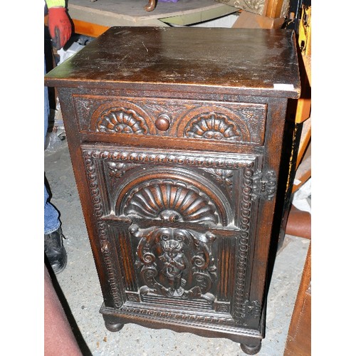 433 - Early to mid 20th Century oak cupboard with drawer, the door deeply carved with a cherub playing a t... 