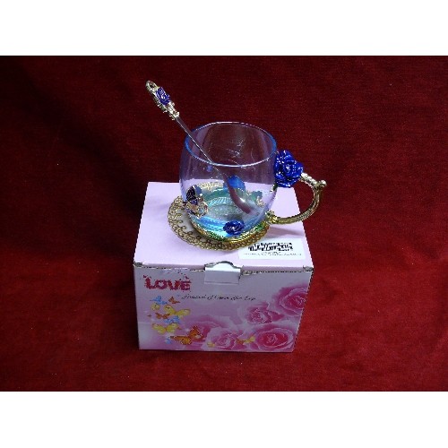 104 - NEW AND BOXED ENAMEL FLOWER TEACUP WITH SPOON.