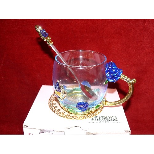 104 - NEW AND BOXED ENAMEL FLOWER TEACUP WITH SPOON.