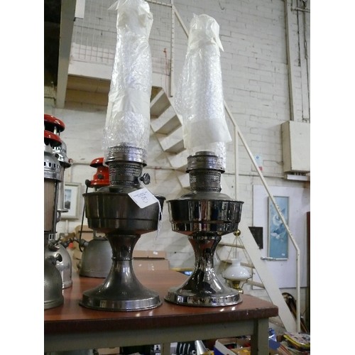 239 - TWO SILVER COLOURED LOXON LAMPS WITH CHIMNEYS.