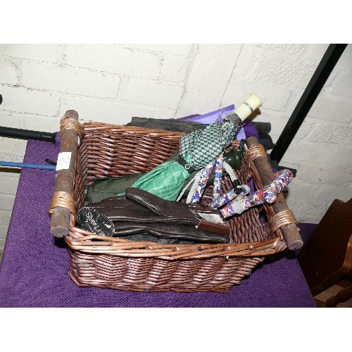 175 - A WICKER BASKET WITH TEN UMBRELLAS, A NEW PAIR OF GLOVES AND A FOLDING WALKING STICK.