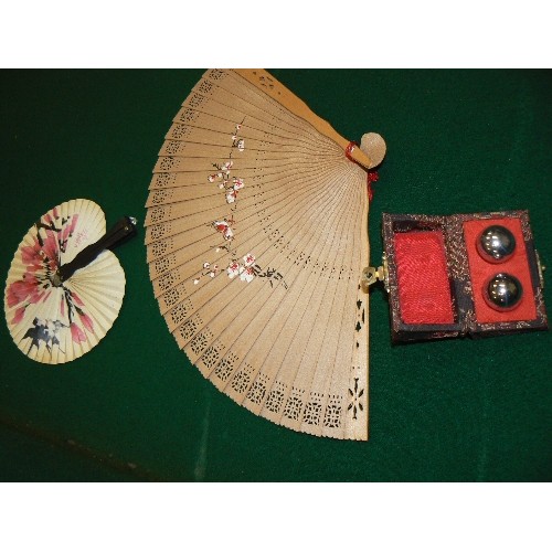 257 - TWO ORIENTAL HAND FANS AND BAODING BALLS IN A FABRIC COVERED BOX.