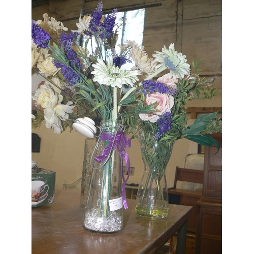 387 - THREE CLEAR VASES WITH ARTIFICIAL FLOWERS.