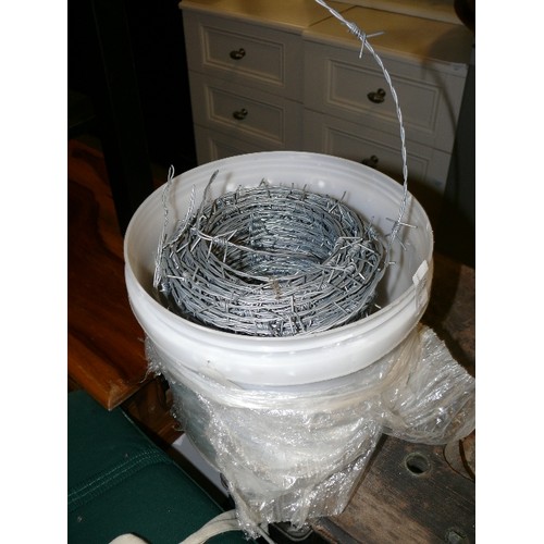 462 - BUCKET CONTAINING A ROLL OF BARBED WIRE.