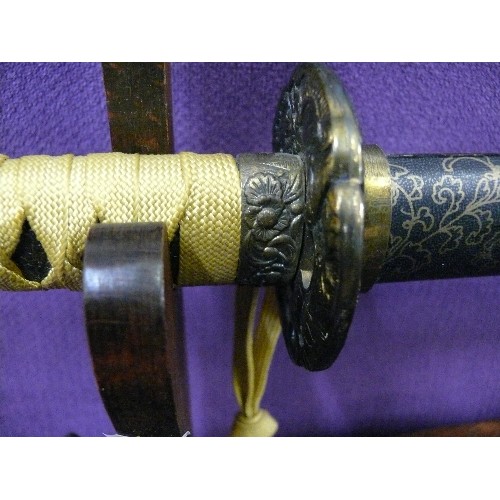 134 - A SET OF THREE ORNAMETAL SAMURAI SWORDS ON STAND.