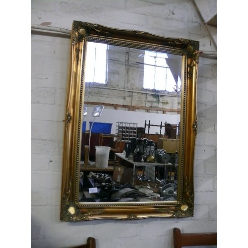 235 - LARGE BEVEL EDGED ORNATE GILT FRAMED WALL MIRROR.