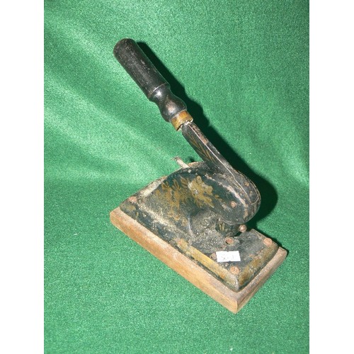 88 - A VINTAGE DECORATIVE CAST IRON HOLE PUNCH WITH WOODEN BASE.