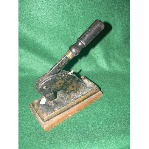 88 - A VINTAGE DECORATIVE CAST IRON HOLE PUNCH WITH WOODEN BASE.